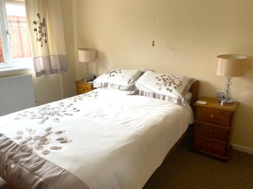 a bedroom with a white bed with pillows and a window at Caerhafod Llangrannog in Llanllwchaiarn