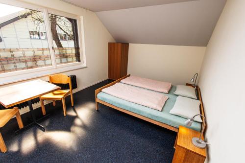 バーデンにあるBaden Youth Hostelのベッドとデスクが備わる小さな客室です。