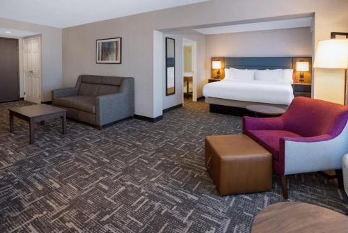a hotel room with a bed and a couch and chair at Wingate by Wyndham Vineland in Vineland