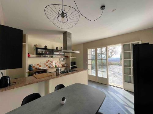eine Küche mit einem Tisch mit Stühlen und einem großen Fenster in der Unterkunft Villa à flanc de colline in Saint-Ambroix