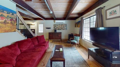 a living room with a red couch and a flat screen tv at Blue Ridge Chalet chalet in Mendon