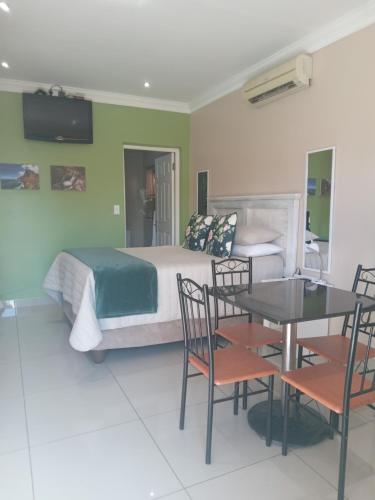 a bedroom with a bed and a table and chairs at SONHOS dreams Self catering Garden Cottages in Bloemfontein