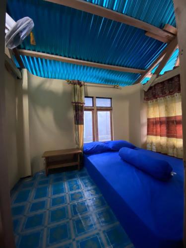 - une chambre avec un lit bleu et un plafond bleu dans l'établissement Dua Putri Komodo Homestay, à Komodo