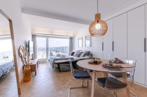 een woonkamer met een tafel en een bank bij Stunning studio with sea-view and terrace in Knokke-Heist