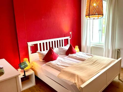 1 dormitorio con paredes rojas y 1 cama blanca con almohadas rojas en Klostermühle Bursfelde, en Hannoversch Münden