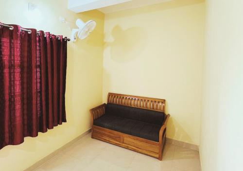 a bench in a room with red curtains at Rivera Holiday Home in Vythiri