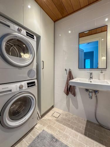 a bathroom with a washing machine and a sink at Solara Suite in Kuningatarranta Hanko in Hanko