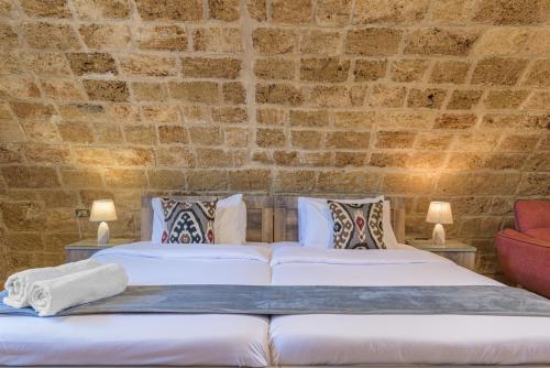 two beds in a room with a brick wall at Timberwood Studio in Batroun in Batroûn
