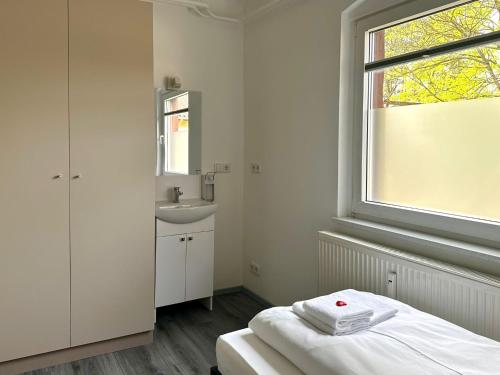 a bathroom with a bed and a sink and a window at Craftsmen´s Comfort - Apartment by Comfort Housing in Falkensee