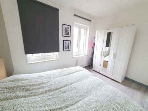 a white bedroom with a bed and a window at C5 Charmant petit deux pièces Centre ville in Cambrai