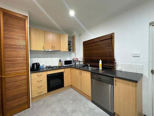 a kitchen with wooden cabinets and a black counter top at Remarkable 2 Bedroom House at the Centre of Darlinghurst in Sydney