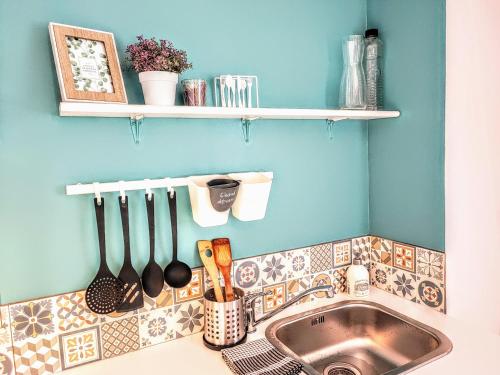 - un évier de cuisine avec des ustensiles sur un mur bleu dans l'établissement Palais du Luxembourg, à Roubaix