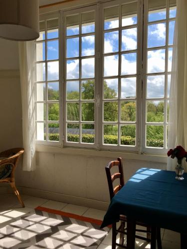 une salle à manger avec une table et une grande fenêtre dans l'établissement Villa des Millepertuis, à Bagnoles-de-l'Orne