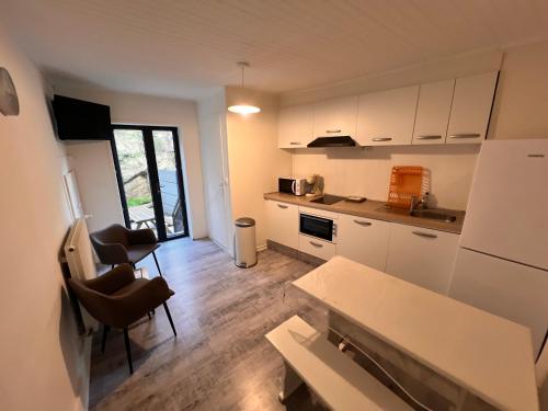 une cuisine avec des armoires blanches et une table et des chaises dans l'établissement Appartement 4 personnes, 1 chambre, terrasse, Wifi, proche du centre, à La Bourboule