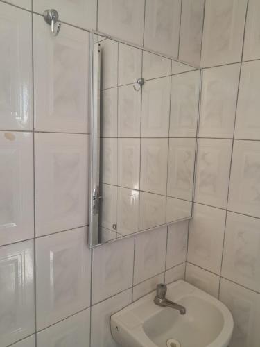 ein weißes Badezimmer mit einem Spiegel und einem Waschbecken in der Unterkunft Hotel e Pousada Mape Ltda in Guanambi