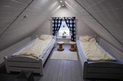 格但斯克新莊園的住宿－Domek pod wierzbami，阁楼卧室设有两张床,配有窗户