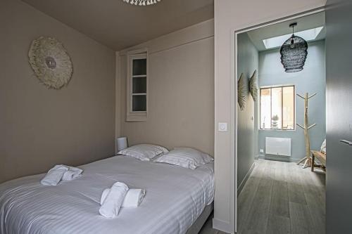 une chambre avec un lit blanc avec des serviettes dessus dans l'établissement LE PETIT MORNY. Apt rénové lumineux et central, à Deauville