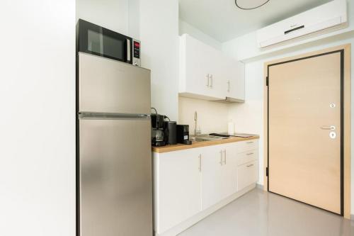 uma cozinha com um frigorífico de aço inoxidável e um micro-ondas em Snug studio apartment with shared garden II em Atenas