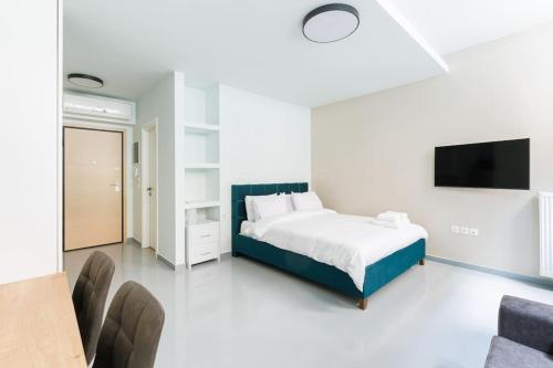 um quarto branco com uma cama e uma televisão em Snug studio apartment with shared garden II em Atenas