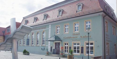 un gran edificio con una escultura de metal delante de él en Hotel Goldener Anker en Radebeul