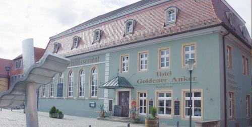 ein großes Gebäude mit einer Metallskulptur davor in der Unterkunft Hotel Goldener Anker in Radebeul