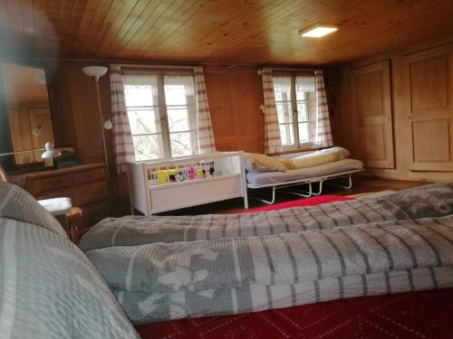 a bedroom with two beds and a couch and windows at Emmental Ferien in Langnau