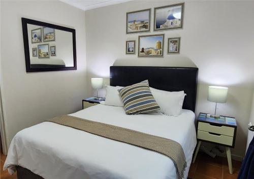 a bedroom with a bed and pictures on the wall at Little Greece in Cape Town