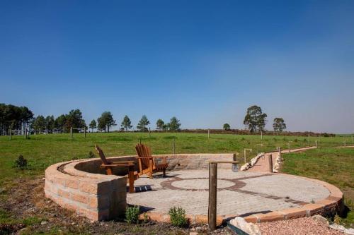 a firepit with a table and chairs in a field at Cabana Fazenda Santa Inês - São Francisco de Paula in São Francisco de Paula
