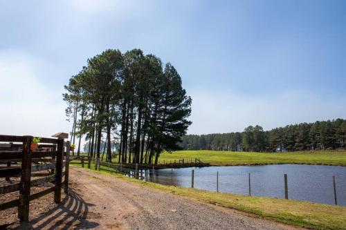 a dirt road next to a fence next to a lake at Cabana Fazenda Santa Inês - São Francisco de Paula in São Francisco de Paula