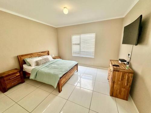 Schlafzimmer mit einem Bett, einem Tisch und einem Fenster in der Unterkunft Coral Bliss in Walvis Bay