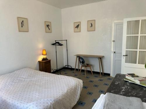 - une chambre avec un lit, une table et un bureau dans l'établissement Petite maison et son jardinet, à Angers
