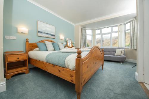 a bedroom with a large wooden bed and a couch at Tyn-y-Coed Inn in Betws-y-coed