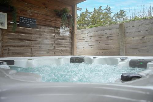 un jacuzzi dans une cour arrière avec une clôture en bois dans l'établissement New - Gite Jennifer piscine et spa, à Saint-Jean-de-Monts