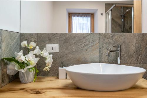 a bathroom with a white sink and a vase of flowers at Casa Graziosa in Campodolcino