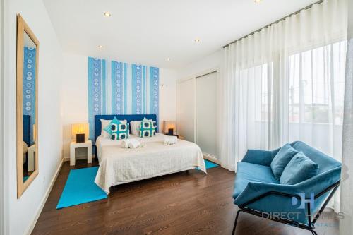 a bedroom with a bed and a blue chair at Villas Rocha in Albufeira