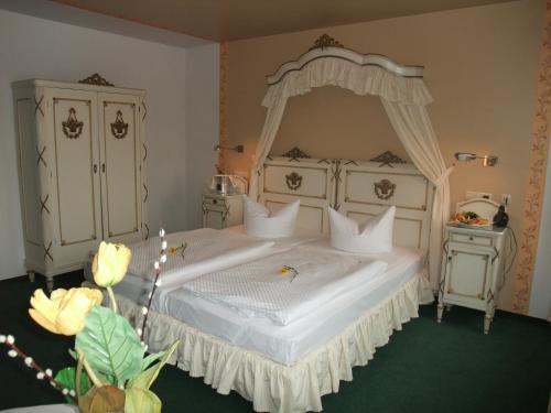 a bedroom with a white bed with a canopy at Hotel Goldener Anker in Radebeul