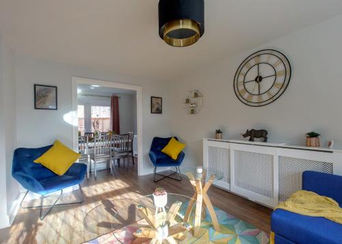 a living room with blue chairs and a table and a clock at Modern House w/Terrace in Nottingham FREE Parking in Nottingham