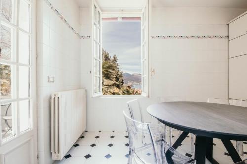 een eetkamer met een tafel en een raam bij The Queen's Suite - Villa Candela in Stresa