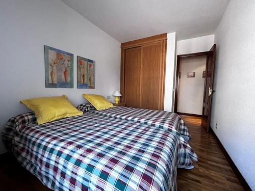 um quarto com uma cama com um edredão xadrez em Piso acogedor y luminoso cerca de hospitales em Pamplona