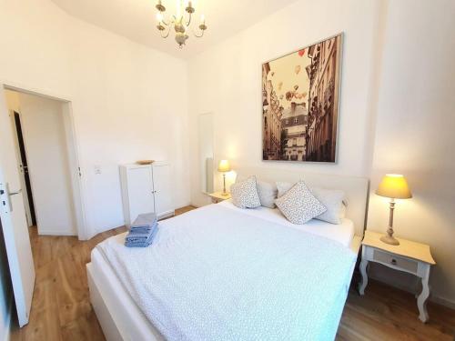 una camera da letto bianca con un letto bianco e un dipinto sul muro di 2 room apt. near station Neustadt in It district a Dresda