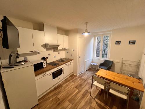 une cuisine avec des armoires blanches et une table en bois dans l'établissement Appartement 4 personnes, wifi, proche centre et thermes, à La Bourboule