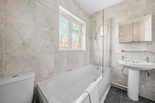 a bathroom with a white tub and a sink at Spacious Luxury Garden House Free Parking in Bristol