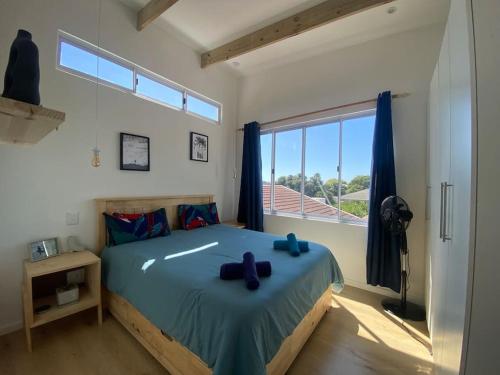 a bedroom with a large bed with blue bows on it at Tree House by the Ocean in Kommetjie