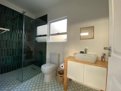 a bathroom with a toilet and a sink and a shower at Tree House by the Ocean in Kommetjie
