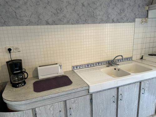 eine Küchentheke mit einer Spüle und einer Kaffeemaschine in der Unterkunft 539 - Maison 5 personnes en plein cœur d'Erquy. in Erquy