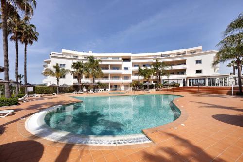 a swimming pool in front of a large building at Villa Mós - Beach Apartments in Lagos