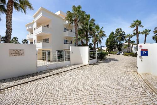 a white building with palm trees in front of it at Villa Mós - Beach Apartments in Lagos