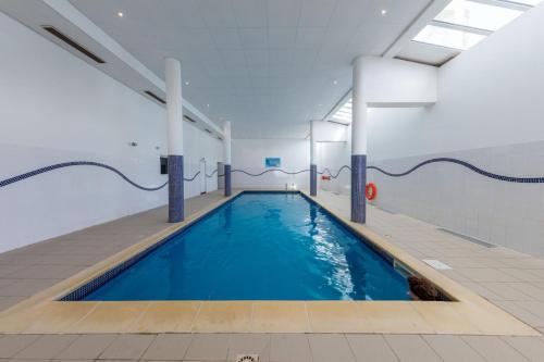 une piscine intérieure d'eau bleue dans un bâtiment dans l'établissement Grand appartement meublé La Foux d’Allos T3 6 à 8 personnes, à Allos