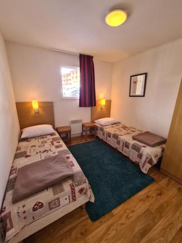 Cette chambre comprend 2 lits et un tapis vert. dans l'établissement Grand appartement meublé La Foux d’Allos T3 6 à 8 personnes, à Allos