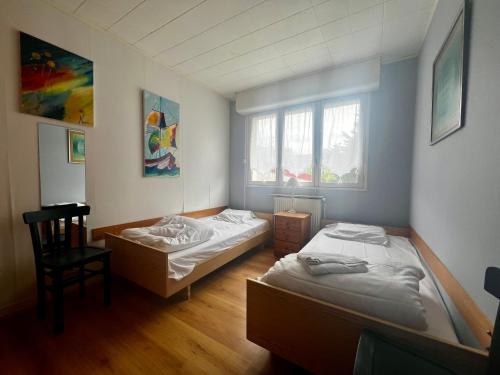 - 2 lits dans une chambre avec une chaise et 2 fenêtres dans l'établissement Le Pédalo - proximité plage, à Wimereux